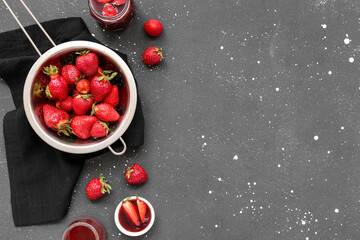 Colander with fresh strawberries and sweet jam on grunge background