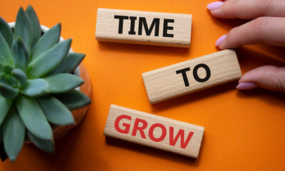 Time to Grow symbol. Concept word Time to Grow on wooden blocks. Businessman hand. Beautiful orange...