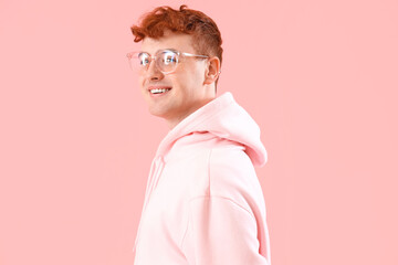 Young redhead man in eyeglasses on pink background