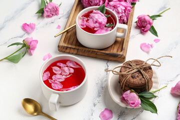 Composition with cups of tea, cookies and beautiful peony flowers on light background