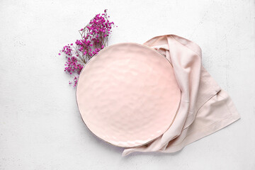 Clean plate with gypsophila flowers and napkin on white table