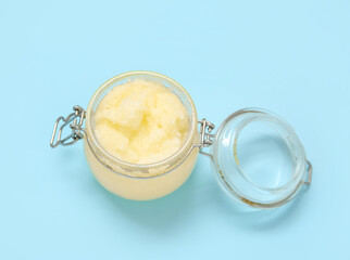 Jar of lemon body scrub on blue background