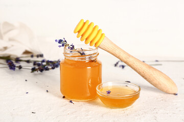 Jar and glass bowl of sweet lavender honey with flowers on white background