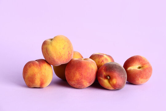 Many sweet peaches on lilac background