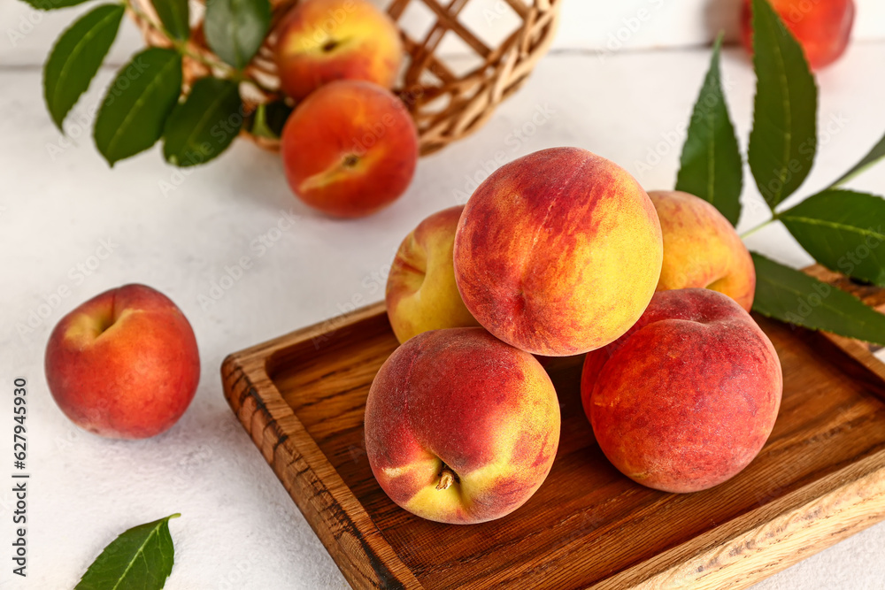 Wall mural wooden board with sweet peaches and leaves on white table