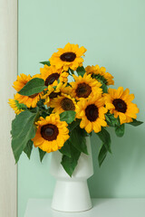 Vase with beautiful sunflowers on white table near green wall © Pixel-Shot