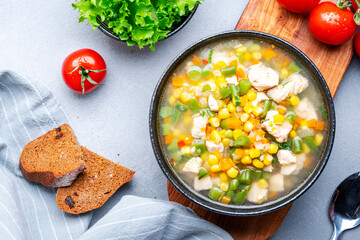 Chicken and vegetable soup with sweet corn and green beans. Comfort food. Gray table background, top view