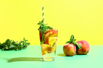 Glass of fresh peach lemonade with mint on colorful background