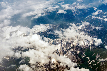 Beautiful window view of fluffy clouds and Alps mountains from passenger seat on airplane. Travel and air transportation