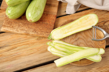 Board and plate with fresh green zucchini on wooden background