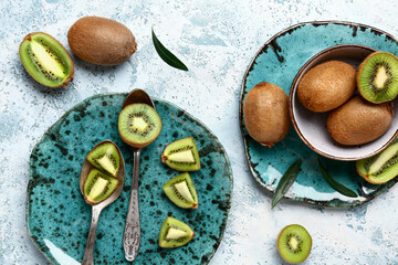 Plate and bowl with fresh kiwi on light blue background