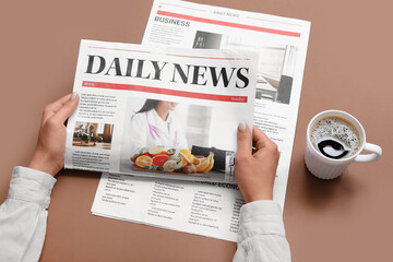 Woman reading newspaper with cup of coffee on brown background - obrazy, fototapety, plakaty