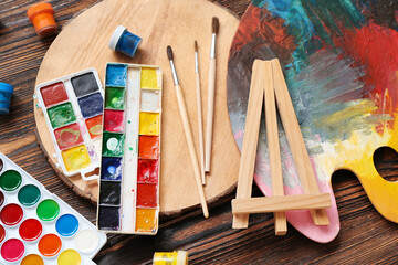 Palette with watercolor paints and brushes on wooden table