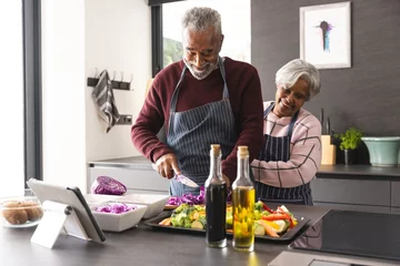 Happy senior biracial couple wearing aprons preparing vegetables in kitchen at home © WavebreakMediaMicro