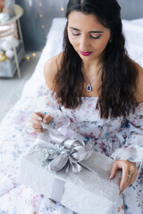 A girl in a white dress unpacks a gift close-up