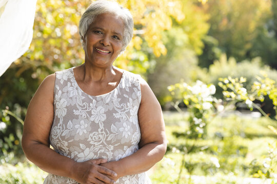 Portrait of happy senior biracial woman smiling in sunny garden at home, copy space