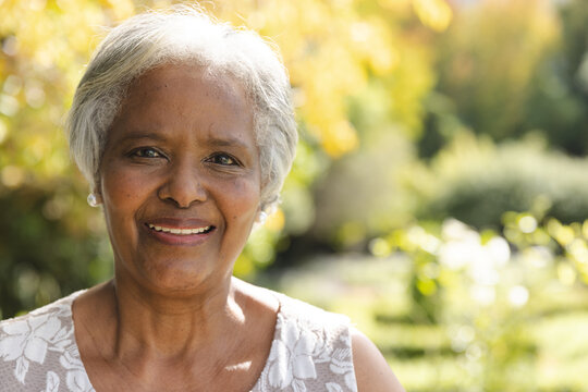 Portrait of happy senior biracial woman smiling in sunny garden at home, copy space
