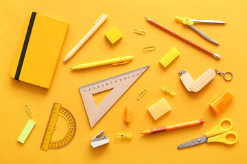 Different school stationery and notebook on orange background