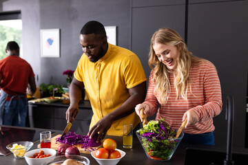 Happy diverse group of friends cutting vegetables on countertop in kitchen
