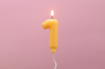 Air balloon shaped birthday candle burning on pink background. Number 1.