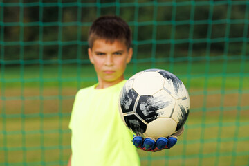 The young goalkeeper holds the ball on his outstretched arm