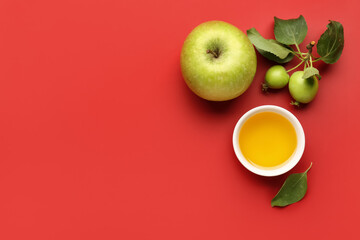 Bowl of honey and apples for Rosh Hashanah celebration (Jewish New Year) on red background