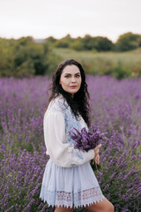 Young woman walking with bouquet of lavender in her hands.