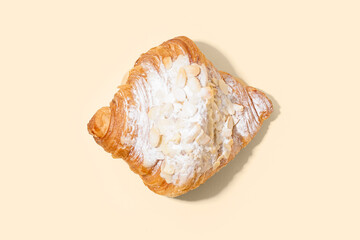 Sweet croissant with powdered sugar and nuts on beige background