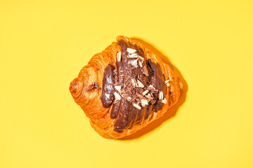 Sweet croissant with chocolate on yellow background