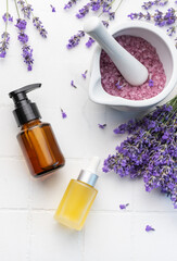 Fototapeta na wymiar Lavender spa. Lavender salt, natural essential oil and fresh lavender on a white tile background.