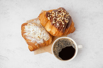 Different sweet croissants and cup of coffee on white background
