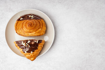 Plate of sweet croissant with chocolate on white background
