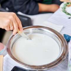 Cut with a knife, separate the serum. Master class and cheese tasting. Women make cheese. The enzyme and starter culture are added to the milk in a metal container. Milk folding process, home