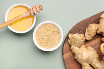 Fresh ginger root and bowl with dried powder on grey background