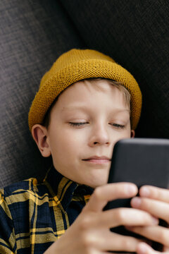 Portrait of caucasian boy enjoying playing mobile games on his smartphone