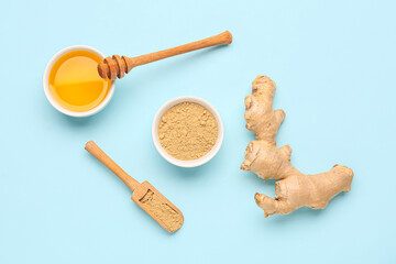 Fresh ginger root, bowl and wooden scoop with dried powder on blue background