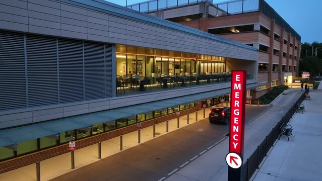 Neon Emergency sign at hospital in USA at night. Aerial establishing shot of emergency room and medical care building.