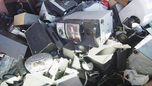 Discarded electronics dumped haphazardly at disposal center, closeup slider