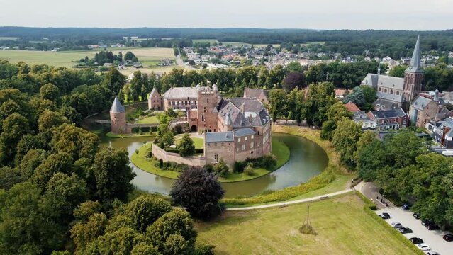 kasteel huis bergh: aerial view in orbit of the fantastic castle and appreciating the moat, the nearby trees, the towers and the nearby church. In the Netherlands on a sunny day.