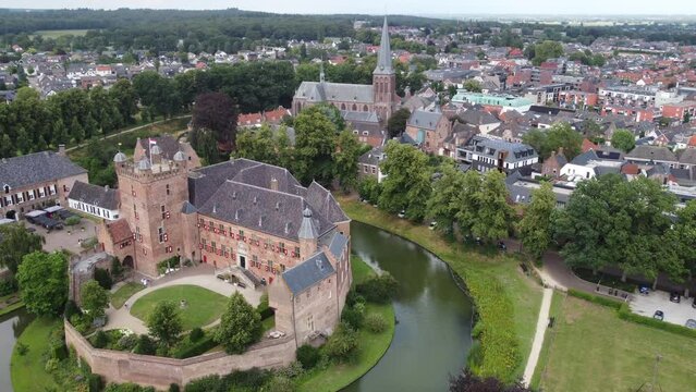 kasteel huis bergh, the netherlands: aerial view in orbit and near the beautiful castle and appreciating the moat and the nearby church. In the Netherlands on a sunny day.