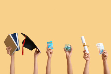 Female hands holding piggy bank, graduation cap, diploma and money on yellow background. Student loan concept