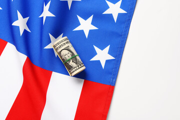 USA flag and roll of dollar banknotes on white background