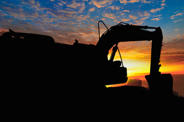 Crawler excavators silhouette are digging the soil in the construction site on the sunset background