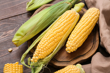 Fresh corn cobs on dark wooden table, closeup