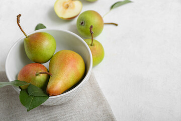Bowl with ripe pears on white table