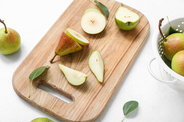 Wooden cutting board with sliced pears on white table