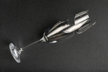 Broken champagne glass on black background from above. © Julia