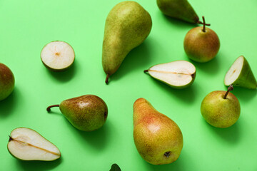 Different types of ripe pears on green background