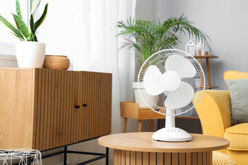Electric fan on wooden coffee table in interior of living room
