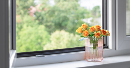 yellow roses in glass vase on windowsill